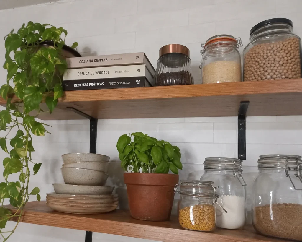 Cozinha moderna com prateleiras de madeira maciça exibindo potes herméticos de vidro e louças artesanais.