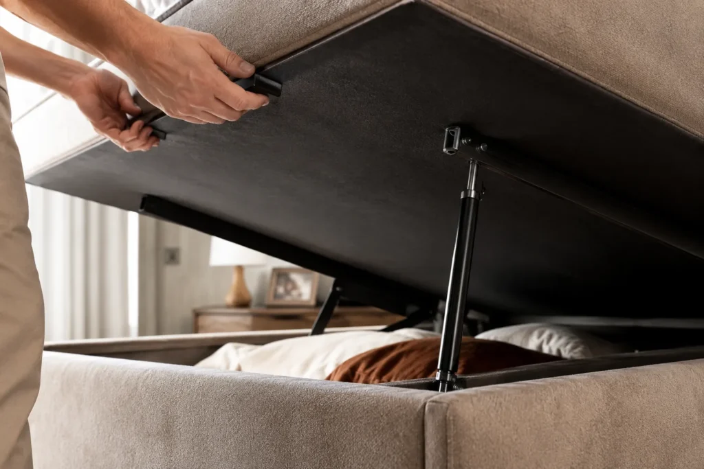 Detalhe de mão levantando a cama box baú mostrando o mecanismo de pistão a gás hidráulico de alta resistência.